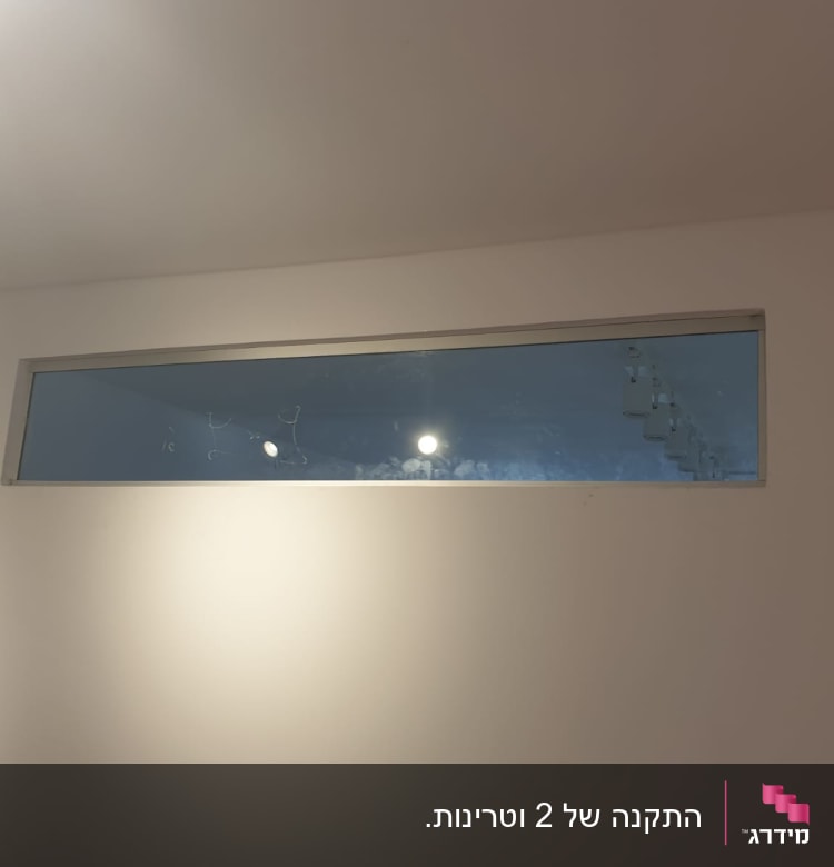 חלון זכוכית מלבני עם מסגרת מתכת בקיר לבן
